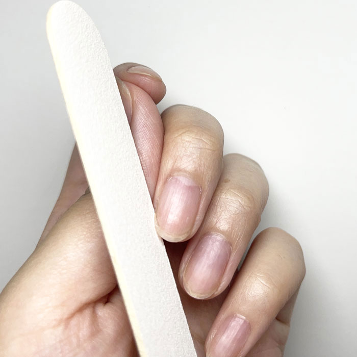 ネイルファイルで自爪の長さと形を整えている様子