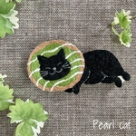 ドーナツ枕で寛ぐ猫の刺繍ブローチ【黒猫×抹茶】