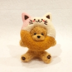 羊毛フェルトの猫ドーナツに顔を入れるトイプードル