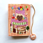 小人さんシリーズ　デコレーションケーキの形のケーキ屋さんの手刺繍　オレンジ色のギンガム　コットンのブックカバー　文庫本サイズ　スィーツ刺繍　手刺繍　ケーキ　童話　メルヘンチック　ギンガムチェック　