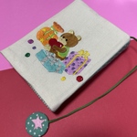 生成り色リネンのブックカバー　色んなプレゼントの手刺繍　しおり付き　くま　クマ　熊　テディベア　ブックカバー　刺繍　手刺繍　文庫本カバー　文庫本サイズ　贈り物　麻　リネン100%  栞付き　いお