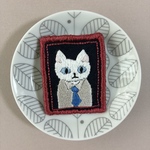 額縁に収まるかしこまったネコの刺繍ブローチ